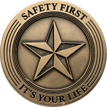 Antiqued bronze challenge coin featuring a raised five-point star with the text Safety First and It's Your Life around the border.