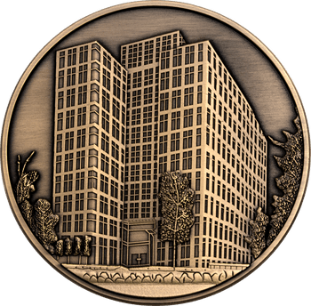Round antique bronze challenge coin featuring a detailed 3D relief of a modern high-rise building with surrounding trees and streetscape.