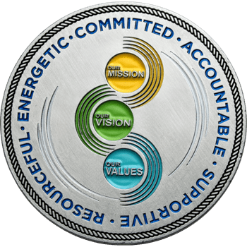 Silver challenge coin with blue outer text and yellow, green, and blue circles labeled Our Mission, Our Vision, and Our Values.