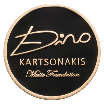 Circular challenge coin featuring a black enamel background with gold Dino Kartsonakis Music Foundation text and signature logo.