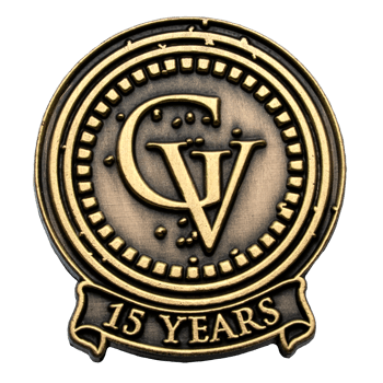 Antiqued gold lapel pin featuring the GV monogram and a banner reading 15 Years.
