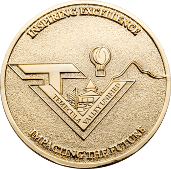 Gold challenge coin featuring the Temecula Valley Unified logo with a hot air balloon, mountain range, and school building illustration.