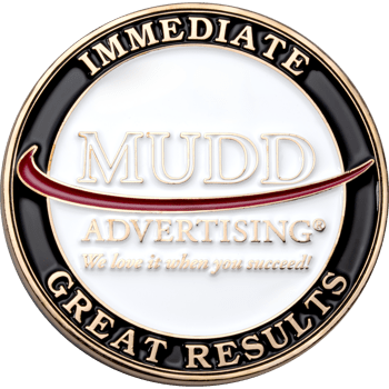 Circular challenge coin for Mudd Advertising featuring gold, black, and white enamel with a red swoosh.