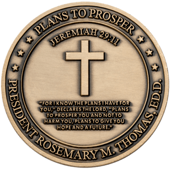 Antiqued bronze challenge coin featuring a central cross, Jeremiah 29:11 scripture, and the name President Rosemary M. Thomas.