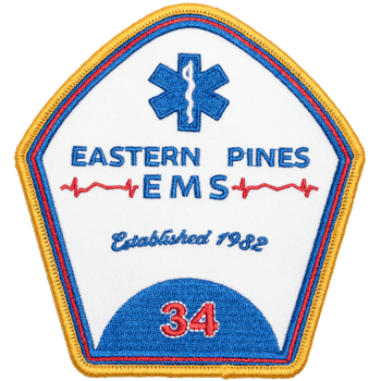 Shield-shaped embroidered patch for Eastern Pines EMS featuring a blue Star of Life, red EKG line, and gold border.
