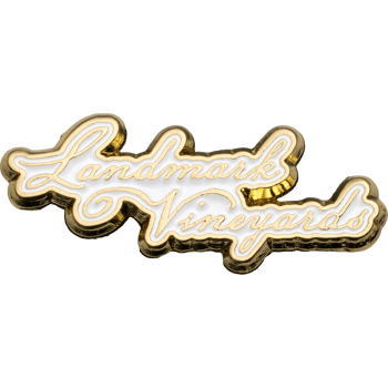 Gold-plated Landmark Vineyards lapel pin with white enamel fill in a cursive script font.