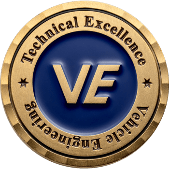 Gold and blue challenge coin featuring VE initials with Technical Excellence and Vehicle Engineering text around a diamond-cut edge.