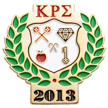 Gold lapel pin featuring red Greek letters KRS, a green laurel wreath, a white shield with symbols, and the year 2013.