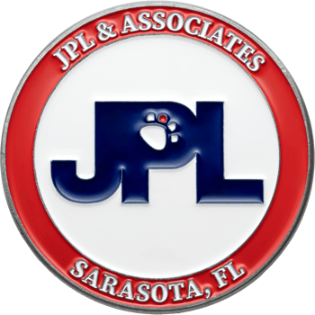 Circular challenge coin with red and white enamel rings featuring the JPL & Associates logo with a paw print detail.