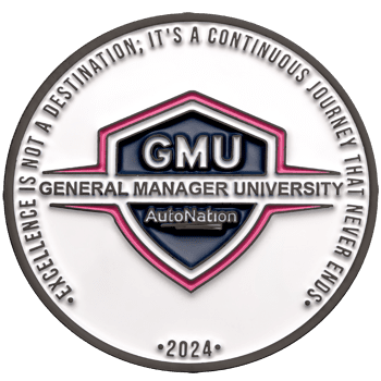 Circular challenge coin for General Manager University AutoNation 2024 featuring a shield emblem and excellence quote on white enamel.
