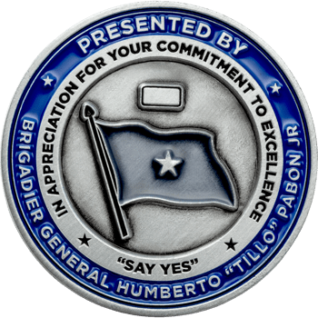 Silver challenge coin with blue enamel border featuring Brigadier General Humberto Pabon Jr text and a star-emblazoned flag in the center.
