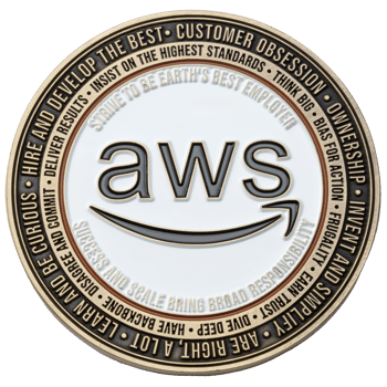 Circular AWS challenge coin with white enamel center and bronze-colored outer rim featuring leadership principles text.